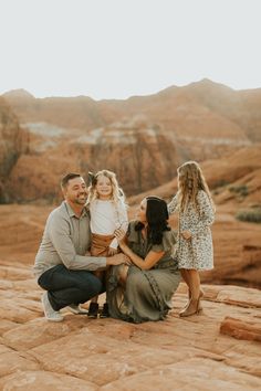 a family sitting on top of a rock in the desert