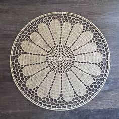 a white doily sitting on top of a wooden table next to a black wall