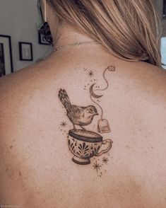 a woman with a tattoo on her back holding a coffee cup and a teacup