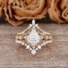 an engagement ring with a pear shaped diamond surrounded by smaller round brilliant cut diamonds on a wooden surface