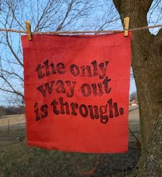 the only way out is through sign hanging on a clothes line in front of a tree