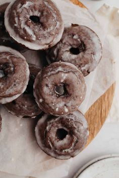 chocolate donuts with icing and sprinkles on a wooden board next to plates