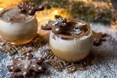 two cups filled with hot chocolate on top of snow covered ground next to christmas decorations