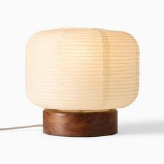 a wooden table lamp with a white shade on it's top and a cord attached to the base