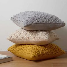 three pillows stacked on top of each other in front of a book and a lamp