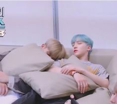 two boys are sleeping on the couch with pillows