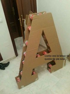 a cardboard letter sitting on the floor with coca - cola cans in front of it