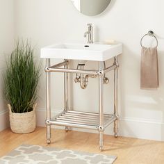 a white sink sitting under a mirror next to a potted plant in a bathroom