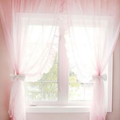 a window with pink curtains and bows on the windowsill, in front of a white bath tub