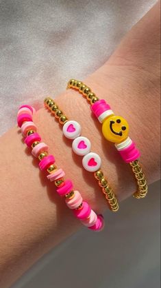 three bracelets with smiley faces and hearts on them, one has a chain around the wrist