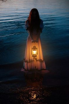 a woman standing in front of the ocean with a lantern on her head and an inspirational quote below