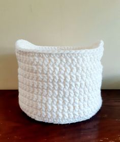 a white crocheted basket sitting on top of a wooden table