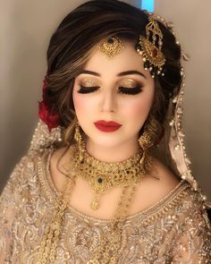 a woman with makeup and jewelry on her face, wearing a bridal outfit that is gold