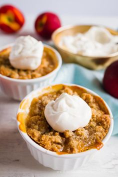 two bowls filled with apple crisp and whipped cream on top of each bowl next to apples