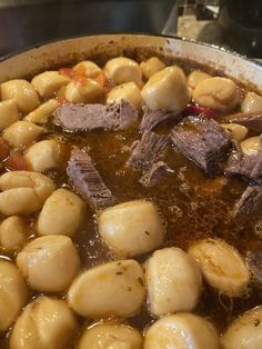 a pot filled with stew and potatoes on top of a stove