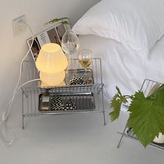 a bed with white sheets and pillows next to a night stand filled with wine glasses