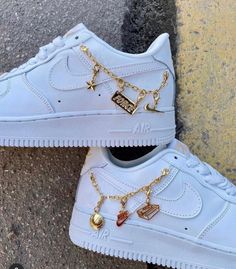 a pair of white nike air force sneakers with gold chains attached to the soles