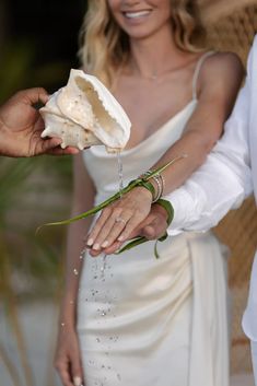 a woman in a white dress is holding a flower