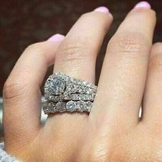 a woman's hand with two wedding rings on top of her finger and the other ring