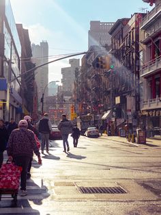 people are walking down the street with suitcases in their hands and one person is crossing the street