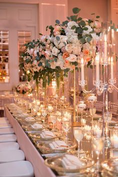 a long table is set with candles and flowers in vases, plates and silverware