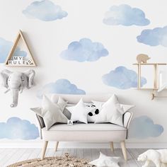 a child's room with blue and white clouds painted on the wall, including an elephant head