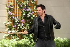 a man in black leather jacket holding a stick