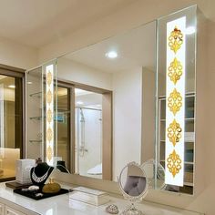 there is a large mirror on the wall in this bathroom that has been decorated with gold and white designs