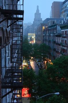 a city street filled with lots of traffic next to tall buildings and trees in the foreground