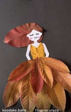 a paper doll sitting on top of a leaf