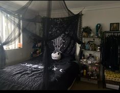 a bedroom with a bed covered in black sheets and decorations on the headboard, windows, and shelves