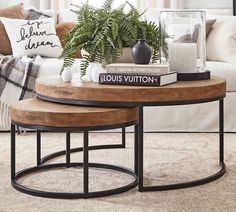 a living room with two coffee tables and plants on the end table in front of the couch