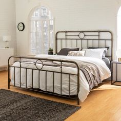 a bed sitting in a bedroom next to a white brick wall and wooden flooring