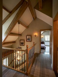 an upstairs view of a bedroom with wood and glass railings, bed in the background