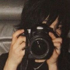 a woman holding up a camera to take a photo in front of her face,