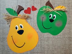 two apples and pears with faces painted on them, one is green and the other is orange