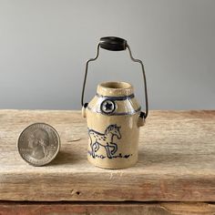 an old fashioned kerosen with a penny sitting next to it on a wooden table