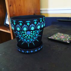 a flower pot sitting on top of a table next to a cell phone