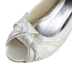 a pair of white high heels with a bow on the toe and heel, all in satin