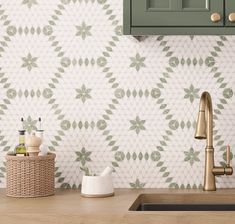 a kitchen with green cabinetry and white wallpaper on the backsplash is shown