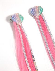 two long pink and green hair with beads on it's ends, one has a shell