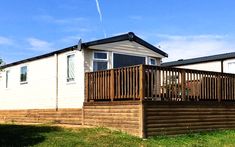 a mobile home with wooden decking and green grass