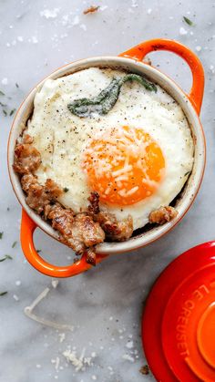 an orange and white bowl filled with eggs on top of a table