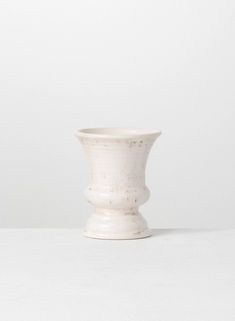 a white vase sitting on top of a table