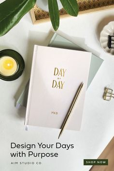 a desk with a notepad, pen and candle next to it that says design your days with purpose