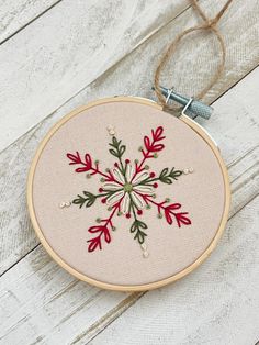 an embroidered snowflake ornament hanging from a string on a white wooden surface