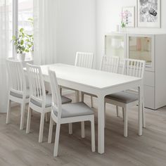 a white dining table with six chairs around it