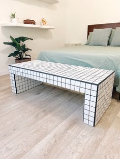 a white and black table sitting on top of a hard wood floor next to a bed