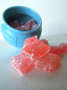 some gummy bears are sitting next to a blue bowl full of sugar cubes