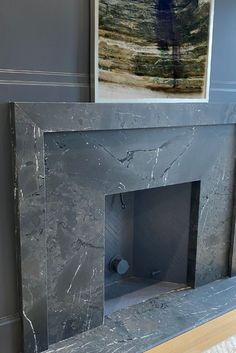 a marble fireplace surround with a painting on the wall